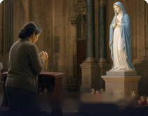 Woman praying before a statue of Mary